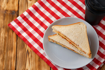 Toast sandwich and cup of coffee on napkin on wooden table