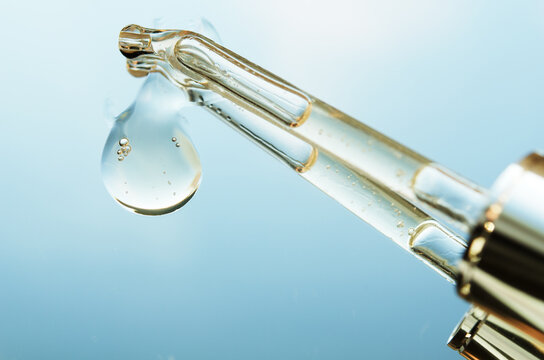 Liquid drop from cosmetic pipette close up, on mirror with reflection. Skin care concept. - Image