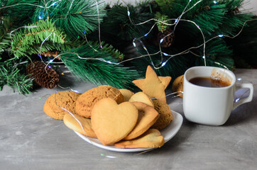 Homemade cookies in the shape of a heart in a white plate with a mug and a tea bag. Christmas...