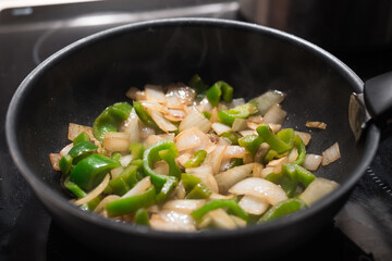 Green peppers and onions sauteed with coco oil in a black pan. Professional cuisine, gourmet asian recipe.