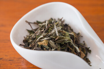 Fototapeta na wymiar Bai Mu Dan (White peony) fresh white tea leaves. From Fujian province, China. Beautiful close up of dry leaves in a porcelain specific container for Gong Fu Cha, the 