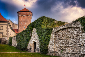 Fototapeta premium Senator's Bastion with the clambering plant covered stone wall of the Wawel Castle in the center of Krakow, Poland below a dark and cloudy sky