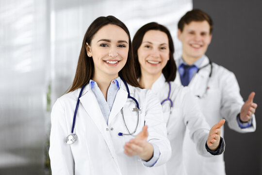 Doctors are standing as a team while offering their helping hands for shaking hand or saving people's life. Physicians are ready to help their patients. Medical help, insurance in health care, best