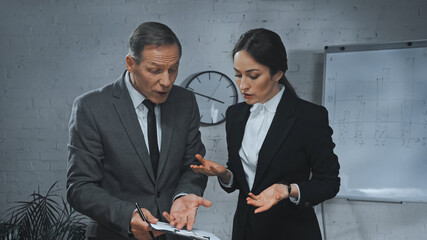  agent pointing at clipboard near colleague in office