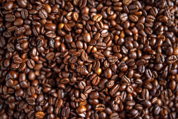 Background of large brown roasted coffee beans close-up.