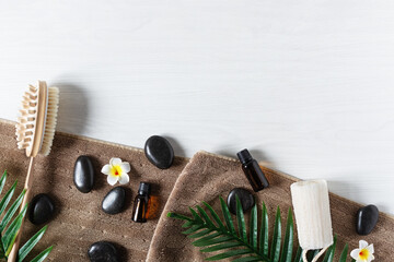 Organic spa products for massage with essential oil and black zen stones top view on white wooden background.