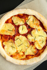 Homemade Margherita Pizza with Mozzarella and Rosemary on a black background, top view. Flat lay, overhead, from above.
