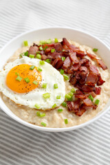 Homemade Cheesy Bacon Savory Oatmeal Bowl on cloth, side view.