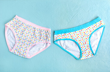 Children's underwear in the form of panties for girls. Children's underwear on a textured blue background. Two panties for a girl. There is space for text.
