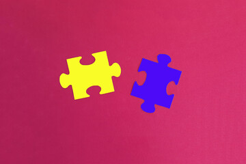 Obraz premium Two puzzles in yellow and blue on a pink background. Interaction, partnership.