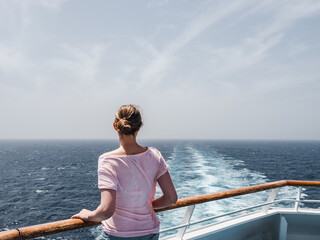 Fashionable woman on the empty deck of a cruise liner against a background of sea waves. Side view,...