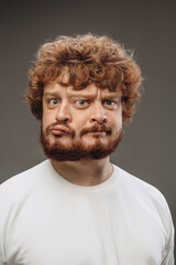 Cute, thoughtful. Young man with dual emotions combination on face isolated on dark background,...