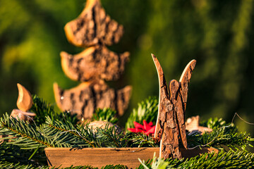 Eine weihnachtliche Holzschale mit einem Engel, einem Tannenbaum, Zweigen und einer Kerze aus Holz