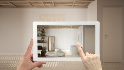 Augmented reality concept. Hand holding tablet with AR application used to simulate furniture and design products in empty interior with ceramic tiles. Bathroom with sofa and shelves