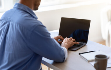 Unrecognizable businessman working on laptop with black screen in office, mockup image