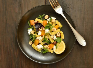 Pasta with baked pumpkin, feta, herbs and hazelnuts,  top view, copy space