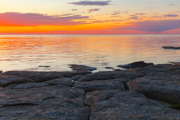 Beautiful colorfull sunset over the sea shore with rocks under shallow water
