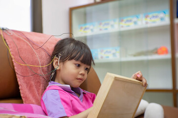 A little girl is wearing a hearing aid and is doing a neurofeedback exam. Making EEG electrodes.