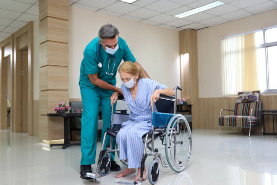 Doctor or assistance staff help or assist a elder patient woman while sitting on wheelchair in the hospital, eldercare concept
