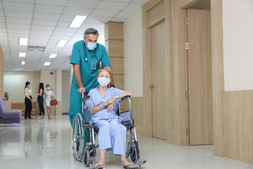 Doctor or assistance staff help or assist a elder patient woman while sitting on wheelchair in the hospital, eldercare concept