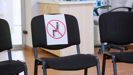 Waiting room in clinic with nobody in it, front office with new normal having sign on chair for social distance in coronavirus pandemic. Empty stomatology reception during covid-19 epidemic.