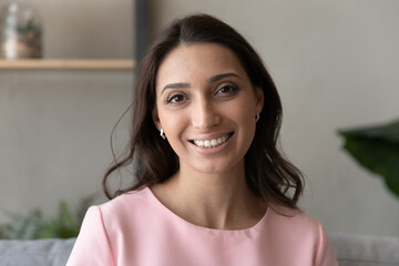 Head shot portrait social networks or dating application profile picture of attractive young happy indian arabic mixed race woman with toothy white teeth and perfect skin, looking at camera.