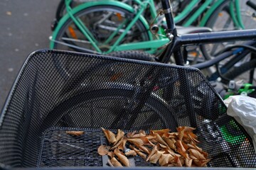 Metal wire basket on a bicycle with some dry leaves in it. It stands among other parked bicycles on the parking lot in the city center of Lucerne, Switzerland. Example of ecological mobility.