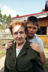 An elderly woman with her grandson outdoors in the village.