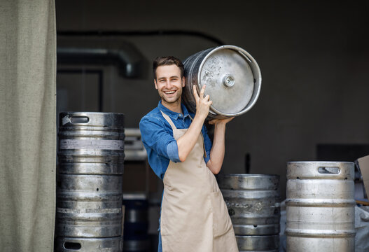 Modern brewery and worker with keg on plant, small business and beer industry