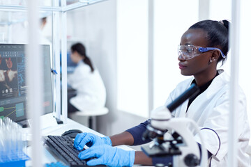 Professional african medical worker typing information about virus study Black healthcare scientist...