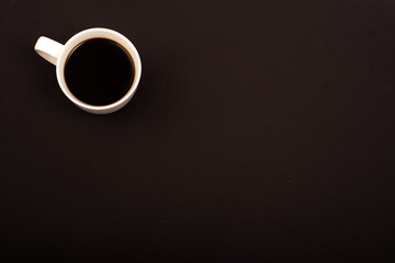 Top view of white ceramic mug with black coffee on black background. Copy space