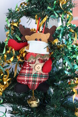 Christmas rein deer wearing medical face mask on Christmas tree . Pandemic Christmas concept.