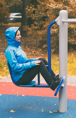 Fototapeta premium Young woman sitting bends her legs during an outdoor training session in Indian summer