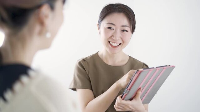 タブレットを使いエステサロンでカウンセリングをする日本人エステティシャン