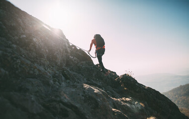 Fototapeta premium Rear view of fully equpped man climbing a mountain