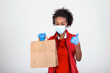 Delivery woman holding paper bag in medical rubber gloves and maskshowing thumb up. copy space. Fast and free Delivery transport . Online shopping and Express delivery . Quarantine