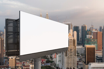 Blank white road billboard with Kuala Lumpur cityscape background at sunset. Street advertising poster, mock up, 3D rendering. Side view. The concept of marketing