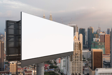 Obraz premium Blank white road billboard with Kuala Lumpur cityscape background at sunset. Street advertising poster, mock up, 3D rendering. Side view. The concept of marketing