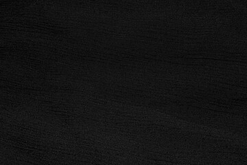 Black dark one-color solid rough textured fabric, textile with folds. Monochromatic template, background