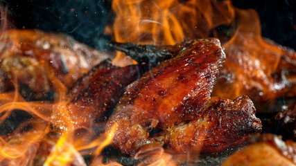 Tasty Chicken Legs on Cast Iron Grate with Fire Flames. Freeze Motion Barbecue Concept.