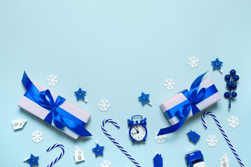 Two gift wrapping, blue ribbon bow, candy on a stick, stars decor, alarm clock, house on a blue background with copy space. Christmas decor frame in minimal style