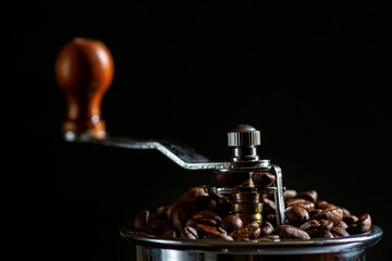 Obraz na płótnie Canvas Roasted coffee beans in a manual ceramic coffee grinder close-up.