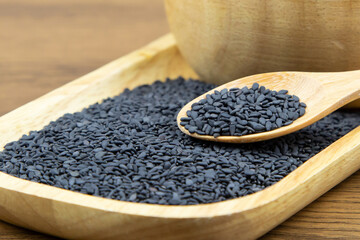 Black sesame seeds in a wooden spoon for healthy food and diet concepts.