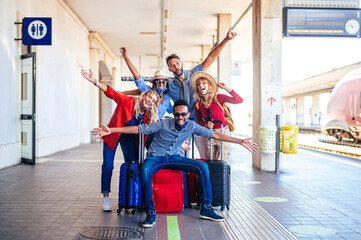 Multiracial group of friends at train station with luggage wearing protective mask -  New normal...