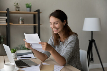 Smiling millennial woman reading postal paper correspondence letter with good news, feeling excited...