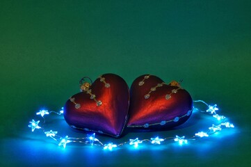 heart-shaped Christmas balls surrounded by lights on a green background