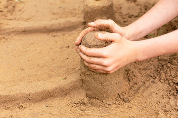 A child builds sand castles on the beach in the summer. Sea tour. Child's hands in the sand. Entertainment in the fresh air