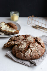 A loaf of rye bread and a sandwich with butter on a black background.