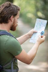 hiker in a forest using map and compass