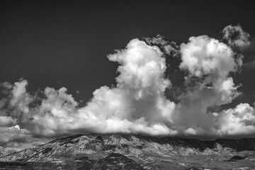 Huge white clouds on dark sky above the mountains in Montenegro, black and white photo.